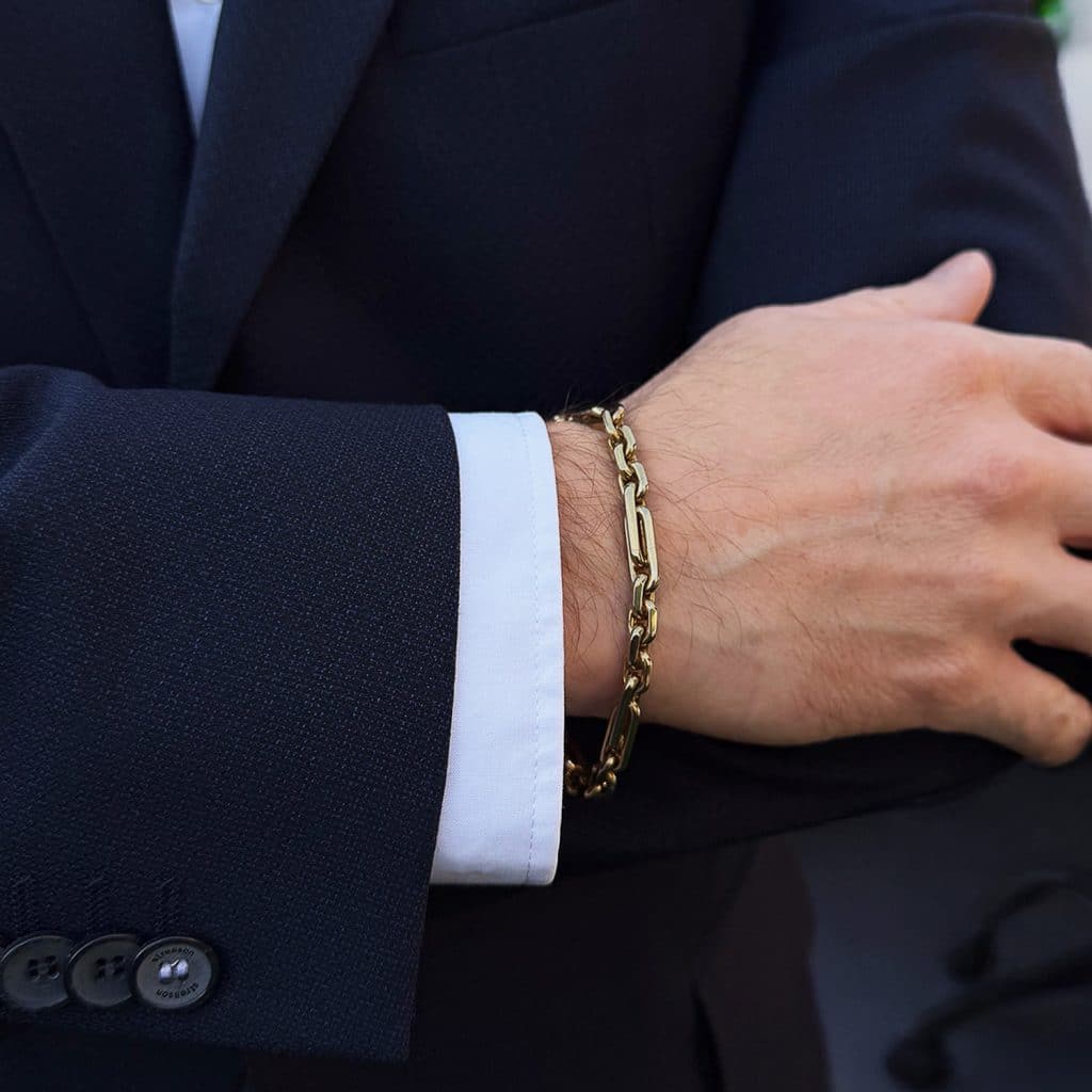 Goldarmbänder für Herren, Massives Herren-Gliederarmband aus Gelbgold, getragen von einem stilvoll gekleideten Mann im Anzug.
