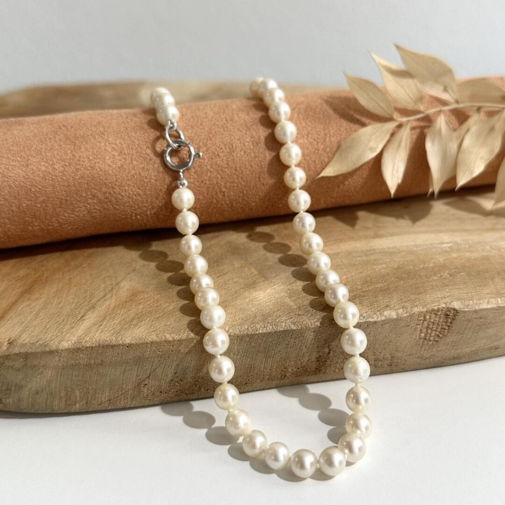 Schlichte Perlenkette für Herren, 48 cm lang, mit 5,5 mm großen Süßwasserperlen und 925-Silber-Springring, elegant auf Holzuntergrund arrangiert.