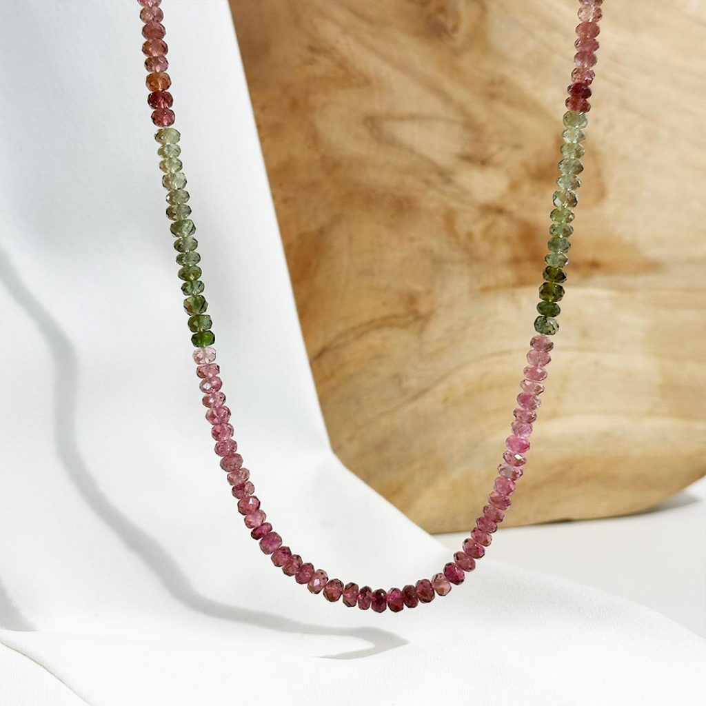 Turmalin Kette mit Farbverlauf, präsentiert auf einem Schmuckaufsteller vor einer eleganten, hellen Holzwand. Artikelnummer 6349