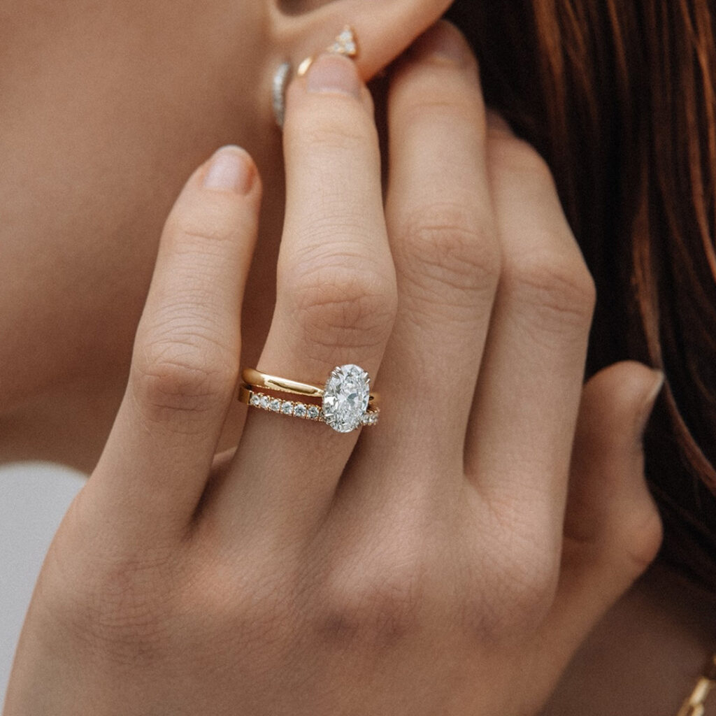 Frau streift sich mit ihrer Hand übers Ohr Verlobungsring im Fokus